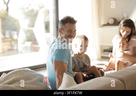 Dad smiling at camera with his family at home Stock Photo