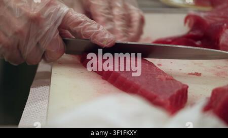 Professional chef slices fresh raw tuna steak on a white cutting board Stock Photo