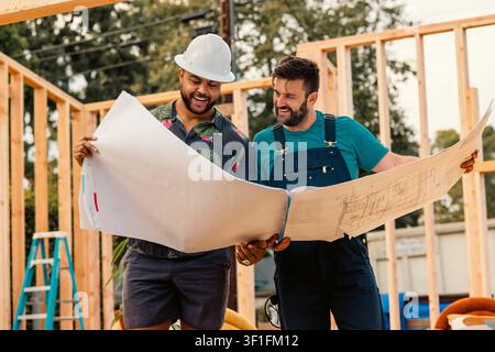 Two men happily review building plans on a construction site Stock Photo