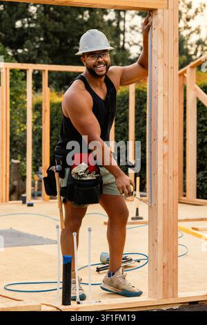 Joyful builder measuring a wooden beam on site Stock Photo