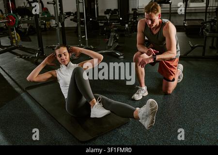 Young Woman Exercising in Gym with Personal Trainer Coaching Stock Photo