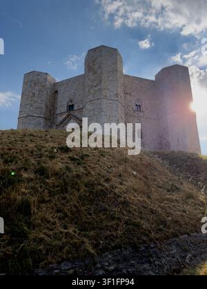 Backlit view of Castel del Monte with the setting sun shining around an octagonal tower near Andria, Apulia, Italy. Stock Photo