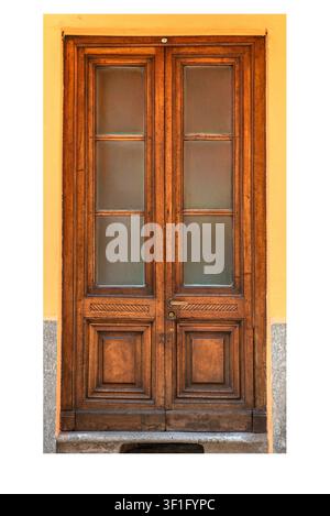 traditional vintage wooden double front door with decorative lower panels and glass windows, set against a vibrant yellow plastered wall in an old Eur Stock Photo