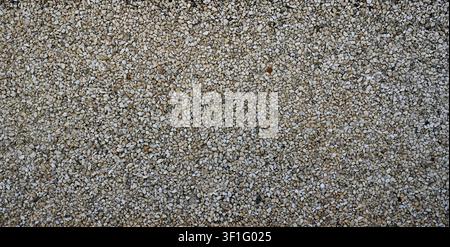 Wall surface with multi size gravel embedded in cement showing rough uneven porous stones in varied colors and shapes Stock Photo