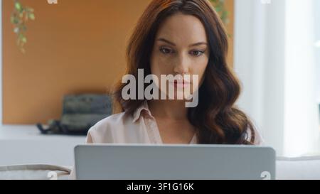 Serious Caucasian woman looking at laptop reading working learning with computer thinking focused busy internet learn study work female business girl Stock Photo