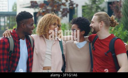 Group of four multiracial students laughing happy hugging in city multiethnic friends candid humorous having fun smiling laugh hug cuddling friendship Stock Photo