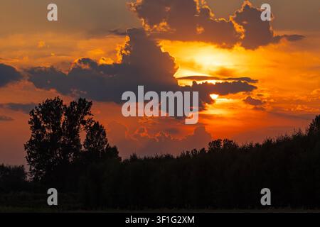 Dramatic golden sunset with bright sun rays shining through dark storm clouds in Poland Stock Photo