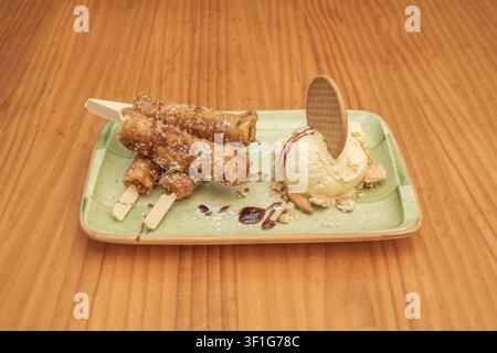 "Fried Turon Rolls on Sticks Served with Vanilla Ice Cream Scoop and Wafer Cookie Garnish" Stock Photo