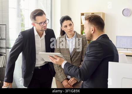 Executives collaborating in office on tablet presentation and strategy meeting Stock Photo