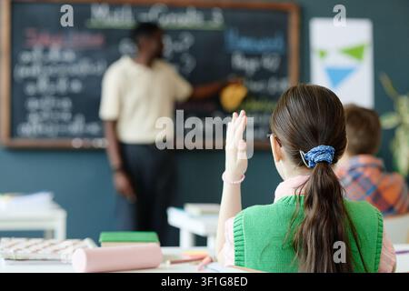 Schoolgirl Raising Hand during Math Lesson for Classroom Learning Stock Photo