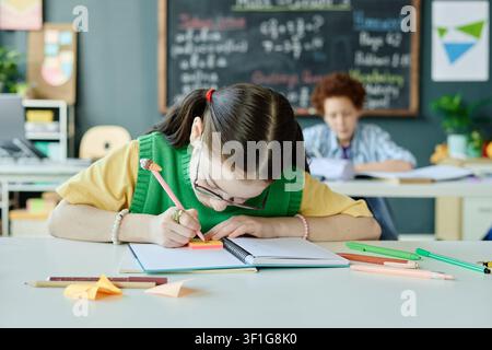 Schoolgirl Writing Notes in Classroom for Learning Support Stock Photo