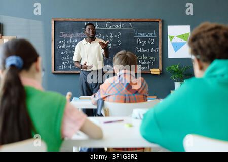 Black Male Teacher Explaining Math Lesson to Elementary Students Stock Photo