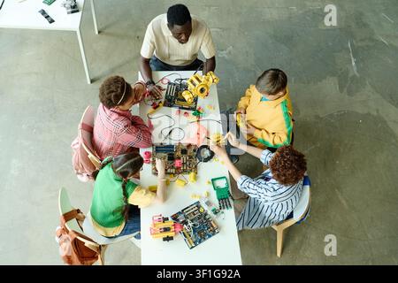Black Male Teacher Coaching Diverse Teenagers in Robotics Workshop Stock Photo
