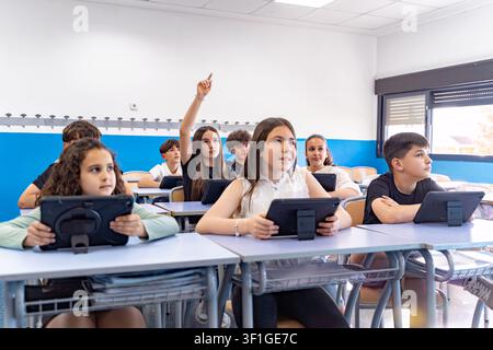 School children using digital tablets for education, actively participating in a modern classroom environment, embracing e learning Stock Photo