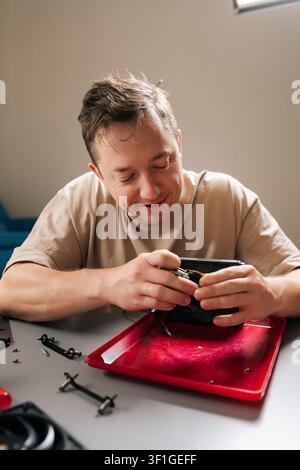Vertical portrait of skilled young man repairing and inspecting all-in-one pc liquid cooler at home, servicing radiator, pump and tubing to maintain Stock Photo