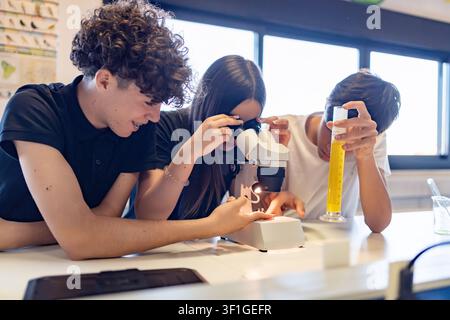 Students actively observing through a microscope during a biology or chemistry lesson, discovering and learning in a school laboratory Stock Photo