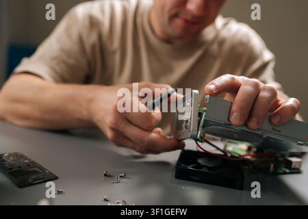 Man focusing on repairing internal computer hardware components with screwdriver, demonstrating expertise in electronics maintenance and technical Stock Photo