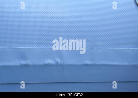 A textured blue vinyl surface with horizontal seam and trim, minimal abstract industrial detail, cool tone, soft lighting evokes calm Stock Photo