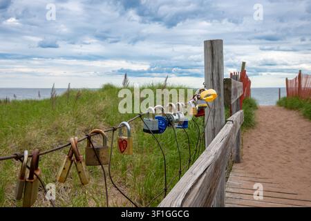 DULUTH, MN - 23 JUN 2026: Colorful padlocks clasped to a wire fence along a sandy beach boardwalk at Park Point, Duluth, Minnesota, with Lake Superior Stock Photo