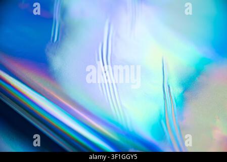 Abstract background featuring iridescent holographic material with swirling textures and a vibrant spectrum of blues, greens, and purples. Soft, diffu Stock Photo