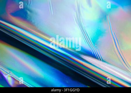 Close up of iridescent holographic material surface showing rainbow spectrum effects and subtle texture. Ideal for futuristic backgrounds, design elem Stock Photo