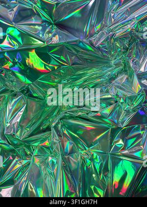 Abstract texture with crumpled green metallic foil reflecting vibrant iridescent colors. High sheen surface creates dynamic shadows and highlights, su Stock Photo