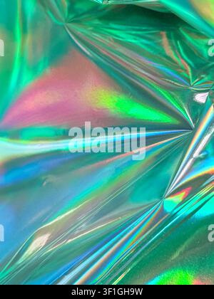 Abstract iridescent foil creating vibrant colorful reflections. Smooth glossy surface with light scattering. Dynamic visual texture suitable for moder Stock Photo