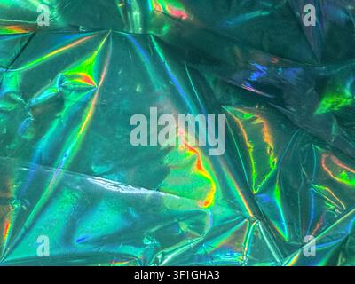 Abstract metallic foil surface with vibrant iridescent colors. Shiny, crinkled texture reflects light, creating holographic effects. Ideal for graphic Stock Photo