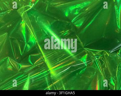 Abstract background featuring crumpled green metallic foil. Shiny textured surface with highlights and shadows, creating a vibrant, dynamic visual. Cl Stock Photo
