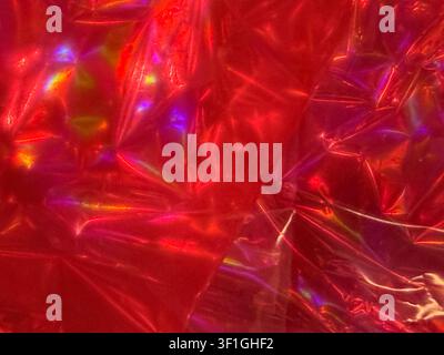 Abstract background with crinkled red holographic material texture. Reflective surfaces create rainbow iridescence and chromatic aberration effects. H Stock Photo