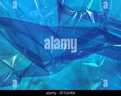 Abstract texture of crumpled blue plastic film with light reflections and shadows. Offers a vibrant color palette and smooth, irregular surfaces ideal Stock Photo