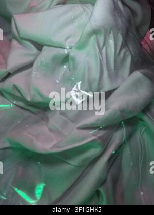 Textured fabric folds with green and pink illumination, creating depth and abstract patterns. Useful for backgrounds, design elements, and creative co Stock Photo