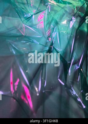 Textured translucent teal plastic sheet with bright pink and purple light reflections. Dynamic abstract background with glossy surface, perfect for cr Stock Photo