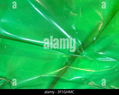 Close up shot of wrinkled green plastic material with highlights creating depth. Displays textured surface and shiny translucent folds. Useful for bac Stock Photo