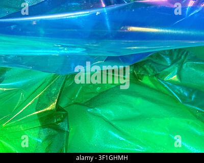 Close up view showcases vibrant blue and green translucent plastic wrap with delicate specular highlights and subtle texture. Abstract background high Stock Photo