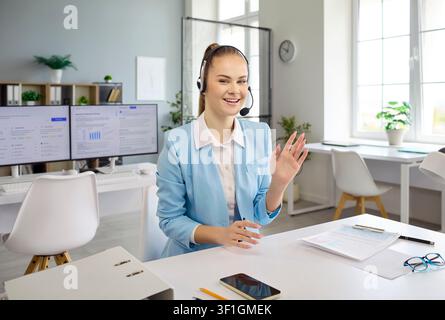 Cheerful customer service representative with headset greeting clients in office Stock Photo