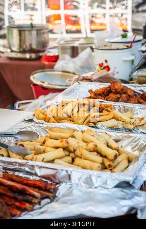 Delicious fried spring rolls and samosas served at an outdoor food stall Stock Photo