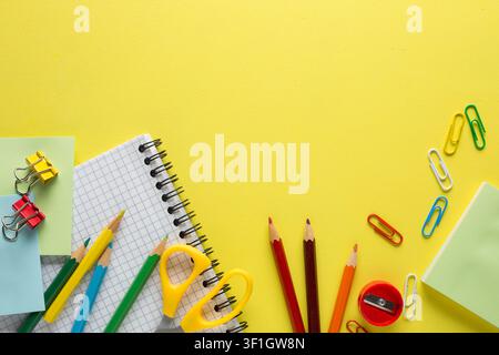 School supplies, colored pencils, notebook on yellow  table. Back to school concept. Flat lay. Stock Photo