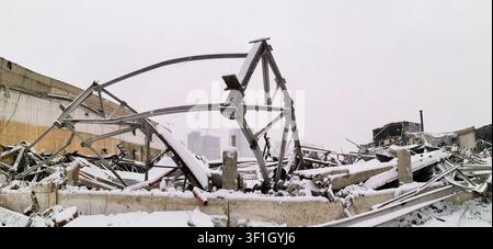 Panoramic view of snow-covered debris from destructed building with steel framework visible. Demolition of old buildings for construction of new ones. Stock Photo