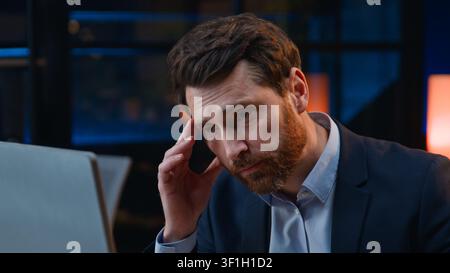 Tired stressed Caucasian middle-aged business man with computer failure at evening overworked employer with desktop problem feeling headache deadline Stock Photo