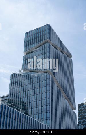 AMSTERDAM, NETHERLANDS - 22 June 2026: Low-angle view of the Mahler 4 Office Tower, also known as the Viñoly Tower, in Amsterdam Zuidas, the Netherlands. Designed by Rafael Viñoly Architects, the 91-metre office building consists of three stacked volumes unified by vertical aluminium fins and an exterior staircase cut into the facade. Stock Photo