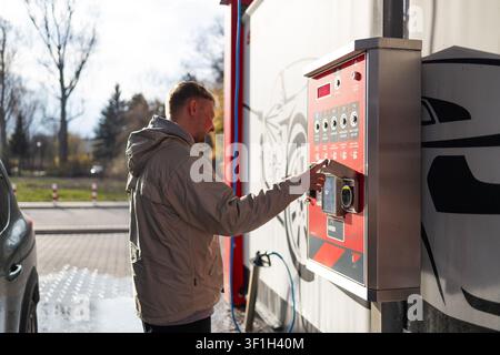 Hand pressing button on automated vending machine at manual carwash station. Stock Photo