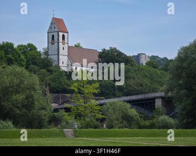 germany, historic st blasius church and graceful bridge framed by vibrant green trees beneath deep blue summer sky in plochingen Stock Photo