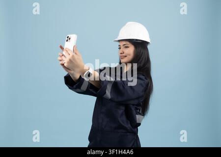 Female construction worker taking selfie photo with mobile smartphone Stock Photo