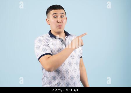 Young male pointing sideways with finger showing direction to copy space Stock Photo