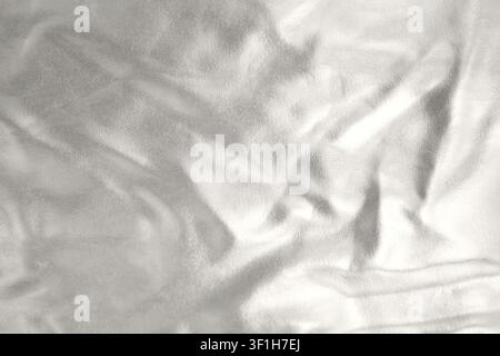 Silver metallic fabric texture with soft wrinkles and abstract reflective background for design Stock Photo