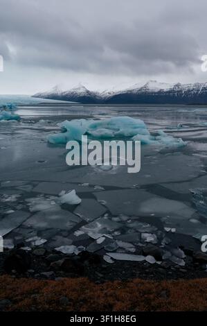 Blue icebergs drift among cracked ice sheets on Jökulsárlón’s frozen lagoon Stock Photo