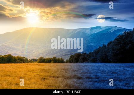 mountain landscape of ukraine. day meet night. sun and moon over alpine grassy meadow and deciduous forest on the hill. equinox nature background for Stock Photo