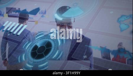Man in suit typing on laptop in tech office, initiating holographic HUD overlaying charts for team Stock Photo