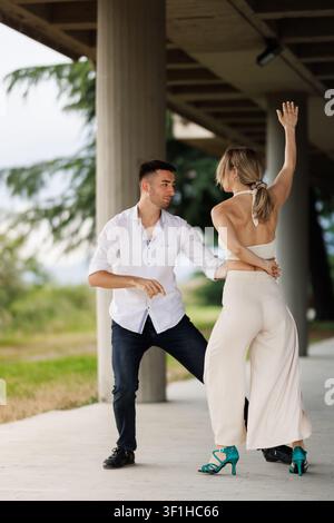 Couple dancing outdoors under pavilion - partners practicing dance moves in a casual summer lesson Stock Photo